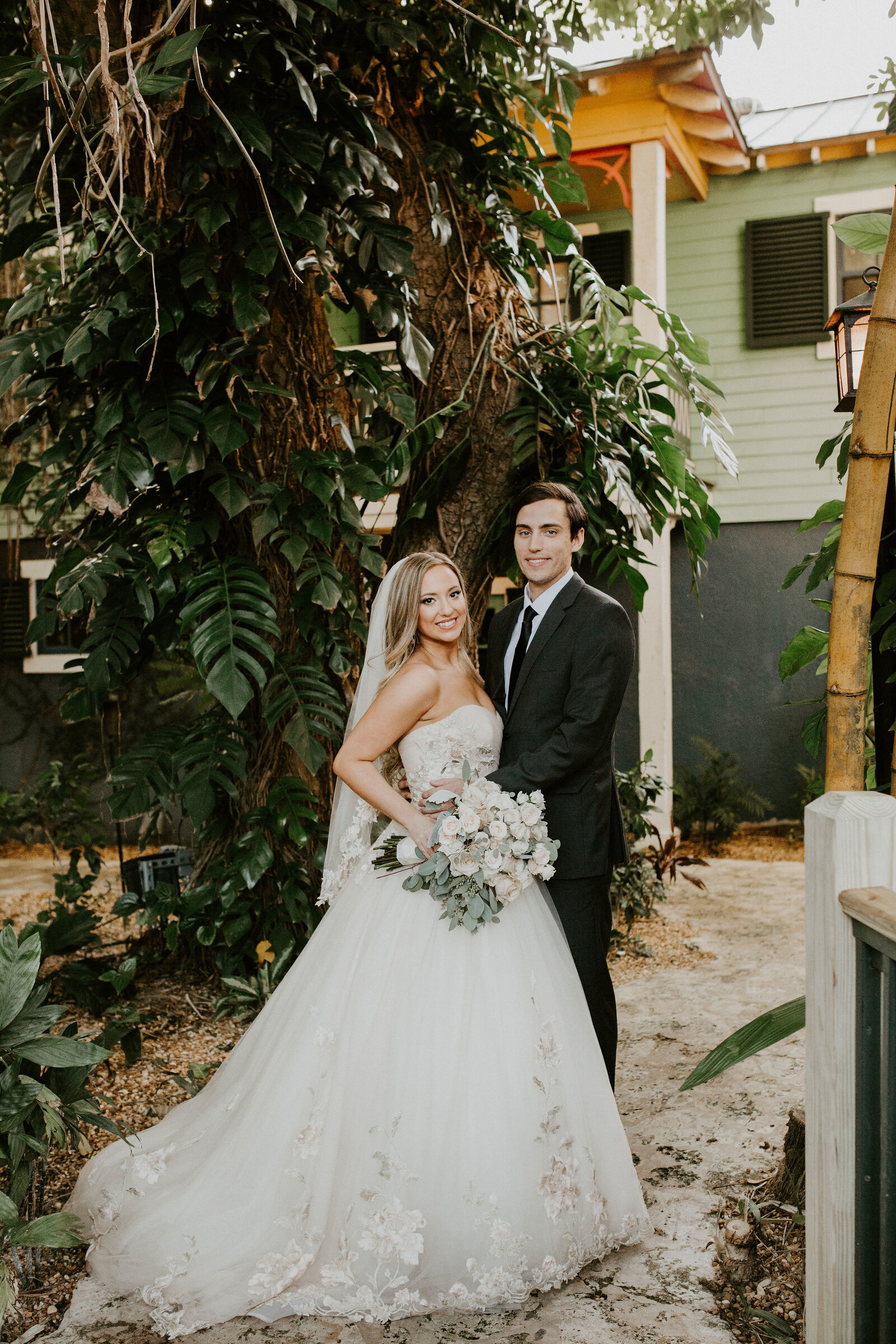 Bride and groom portrait among the lush tropical gardens of their Palm Beach wedding venue