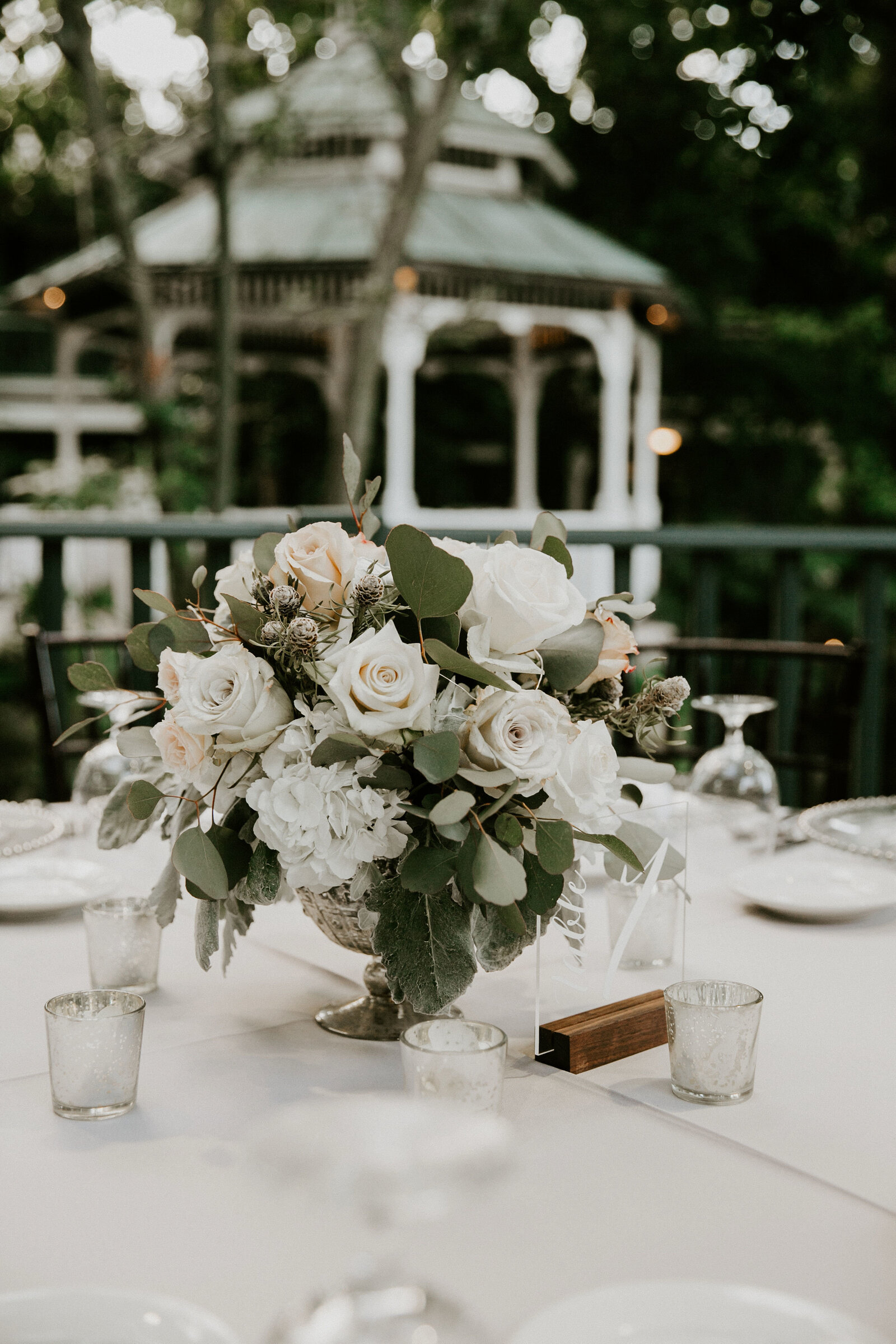 Reception tablescape with a low centerpiece, candlelight and fine place settings