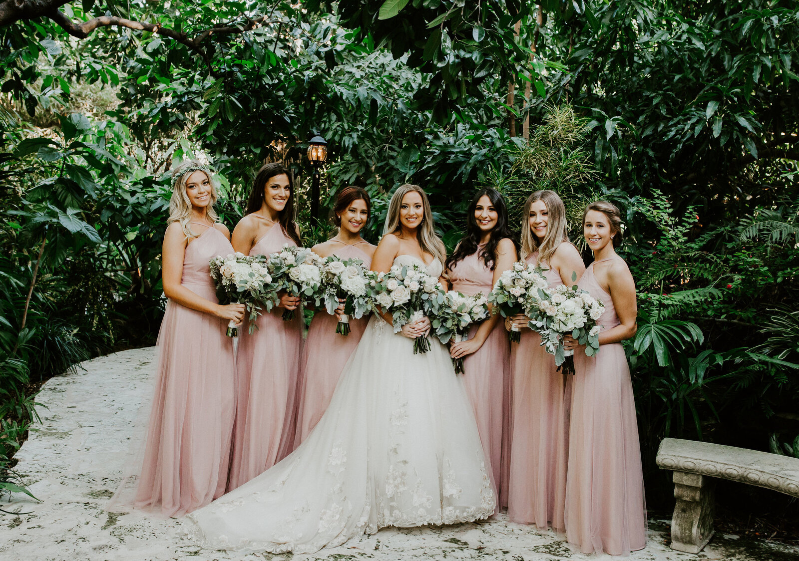 The bride with her bridesmaids in blush gowns in the garden